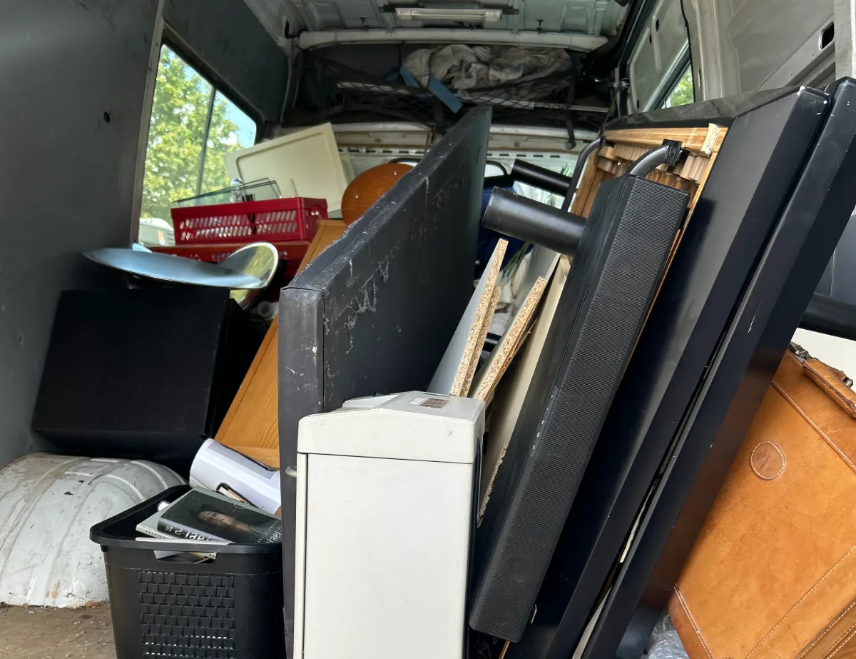 Voll beladener Transporter bei einer Entrümpelung: Fernseher, Koffer, Kisten und Kleingeräte für den Abtransport