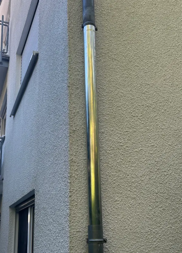 Das neu eingesetzte Stück Fallrohr an der Hauswand, oben und unten schließen die alten Rohrabschnitte an